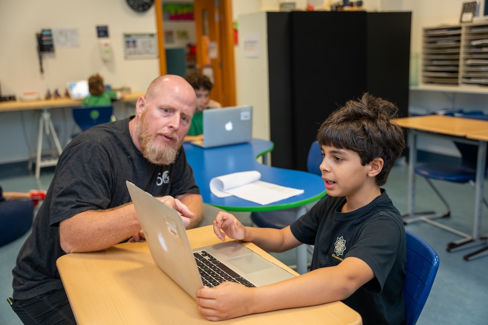 male teacher with child working together with a computer